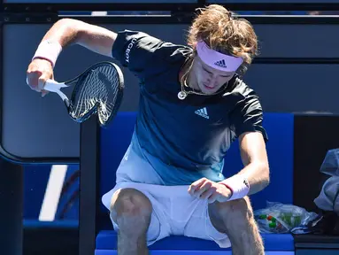 Petenis Jerman, Alexander Zverev membanting raketnya hingga rusak saat beristirahat pada putaran keempat Australia Terbuka  menghadapi Milos Raonic dari Kanada di Melbourne, Senin (21/1). Zverev frustasi setelah kalah dua set 6-1 4-1. (Paul Crock/AFP)