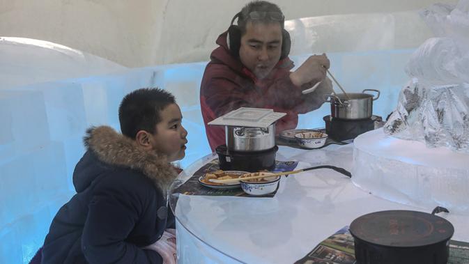 Foto yang diambil 13 Januari 2020 menunjukkan orang-orang menikmati hot pot di meja dan kursi berukir es di dalam igloo selama Festival Es dan Salju Internasional Harbin tahunan. Restoran berbentuk rumah salju bangsa Eskimo ini hadir untuk memberikan sensasi makan malam yang berbeda. (STR/AFP)