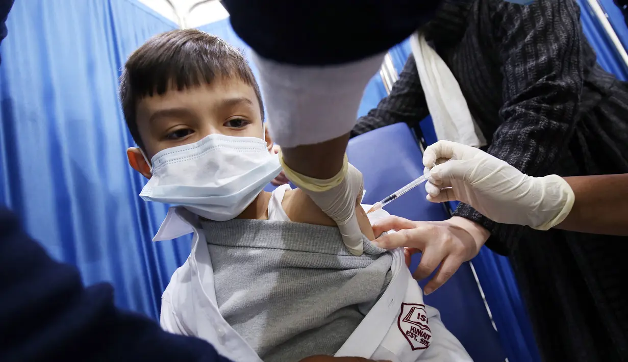 Seorang anak laki-laki menerima dosis vaksin covid-19 Pfizer-BioNTech di pusat vaksinasi di Kuwait International Fairground di Kuwait City pada 3 Februari 2022. Kementerian kesehatan Kuwait mulai memvaksinasi anak usia 5 hingga 11 tahun. (YASSER AL-ZAYYAT / AFP)