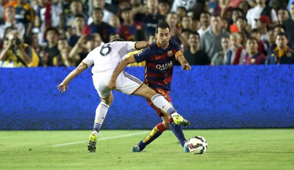Gelandang Barcelona, Sergio Busquets berusaha melewati Stevan Gerrard pada laga International Champions Cup 2015 di Rose Bowl, California, Rabu (22/7/2015). Barcelona menang 2-1 atas LA Galaxy. (AFP PHOTO/Stephen Dunn)