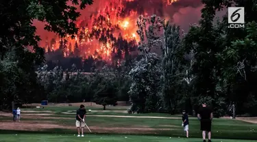 Sejumlah pria santai bermain Golf dengan latar belakang kebakaran hutan di Amerika Serikat.