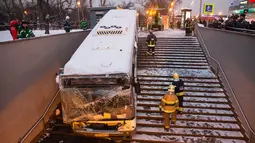 Petugas layanan darurat berusaha mengevakuasi bangkai bus yang hilang kendali dan masuk ke dalam tangga menuju jalan bawah tanah di Moskow, Rusia, Senin (25/12). Sopir bus yang diduga mabuk itu sudah berada ditangani pihak berwajib. (AP/Ivan Sekretarev)