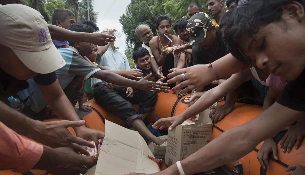 Petugas membagikan makanan kepada korban banjir di Gauhati, India, Rabu (14/6). Angin monsun yang mendatangi India berdampak pada tingginya curah hujan yang menyebabkan banjir. (AP Photo / Anupam Nath)