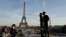 Sepasang suami istri berciuman pada Hari Valentine ketika mereka berdiri di Trocadero Plaza dekat Menara Eiffel di Paris, Prancis (14/2). (AFP Photo/Ludovic Marin)
