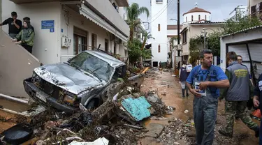 Warga mencoba membersihkan jalan dari puing-puing setelah hujan lebat di desa Malia, pulau Kreta, Yunani, Selasa (10/11/2020). Banjir besar di Pulau Kreta Yunani merusak jalan, membanjiri ratusan rumah, dan menyeret mobil ke laut di tengah hujan deras yang sedang berlangsung. (AP Photo/Harry Nakos)