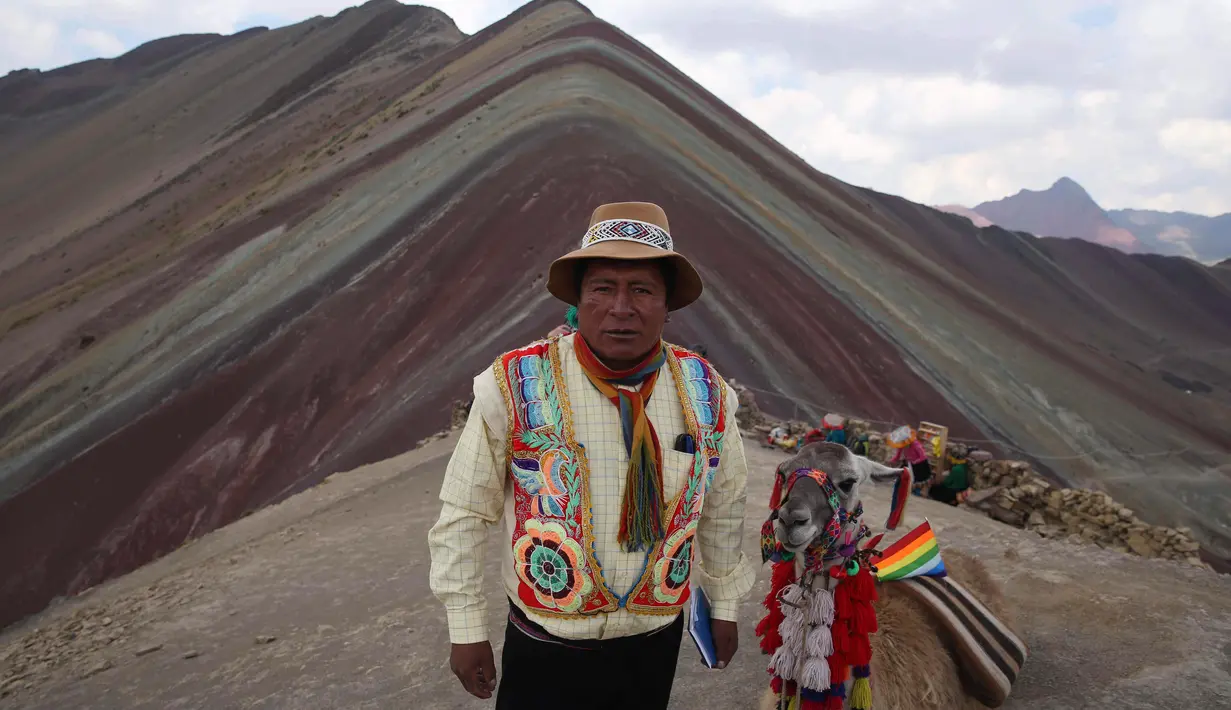 Seorang pria Andes berpose bersama llamanya di Gunung Pelangi di Pitumarca, Peru (2/4). Makin banyaknya wisatawan untuk melihat keindahan gunung tersebut menjadi ladang pekerjaan baru bagi warga sekitar. (AP Photo/Martin Mejia)