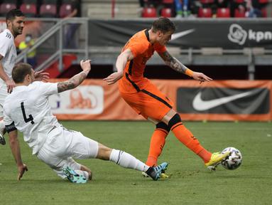 Penyerang timnas Belanda, Wout Weghorst mencetak gol kedua timnya saat pemain bek timnas Georgia, Guram Kashia berusaha memblokir tendangannya dalam pertandingan uji coba jelang Piala Eropa 2020 di De Grolsch Veste, Minggu (6/6/2021). Belanda menang meyakinkan 3-0. (AP Photo/Peter Dejong)