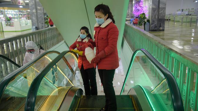 Petugas melakukan penyemprotan cairan desinfetan pada tangga eskalator di Pyongyang Department Store No. 1, di Pyongyang, Korea Utara, Senin (28/12/2020). (AFP/Kim Won Jin)