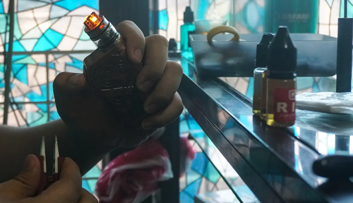 Seorang pelanggan mempersiapkan rokok elektrik di sebuah toko vape di Manila (20/11/2019). Presiden Filipina Rodrigo Duterte mengumumkan akan melarang penggunaan e-rokok dan memerintahkan polisi untuk menangkap orang-orang yang merokok e-rokok di depan umum. (AFP Photo/Dante Diosina Jr)
