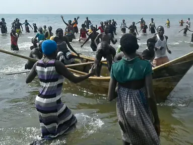 Sejumlah korban selamat dari insiden kapal tenggelam kembali ke darat di Danau Albert, Butiaba, Uganda, Senin (26/12). Setidaknya 30 orang dipastikan menjadi korban dalam insiden tersebut, yang di antaranya terdapat pesepakbola dalam satu tim. (AFP Photo)