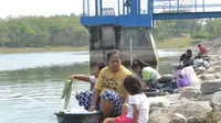 Sembari mengasuh anak, ibu-ibu nekat mencuci di bibir Waduk Sangge. Foto: (Felek/Liputan6.com)