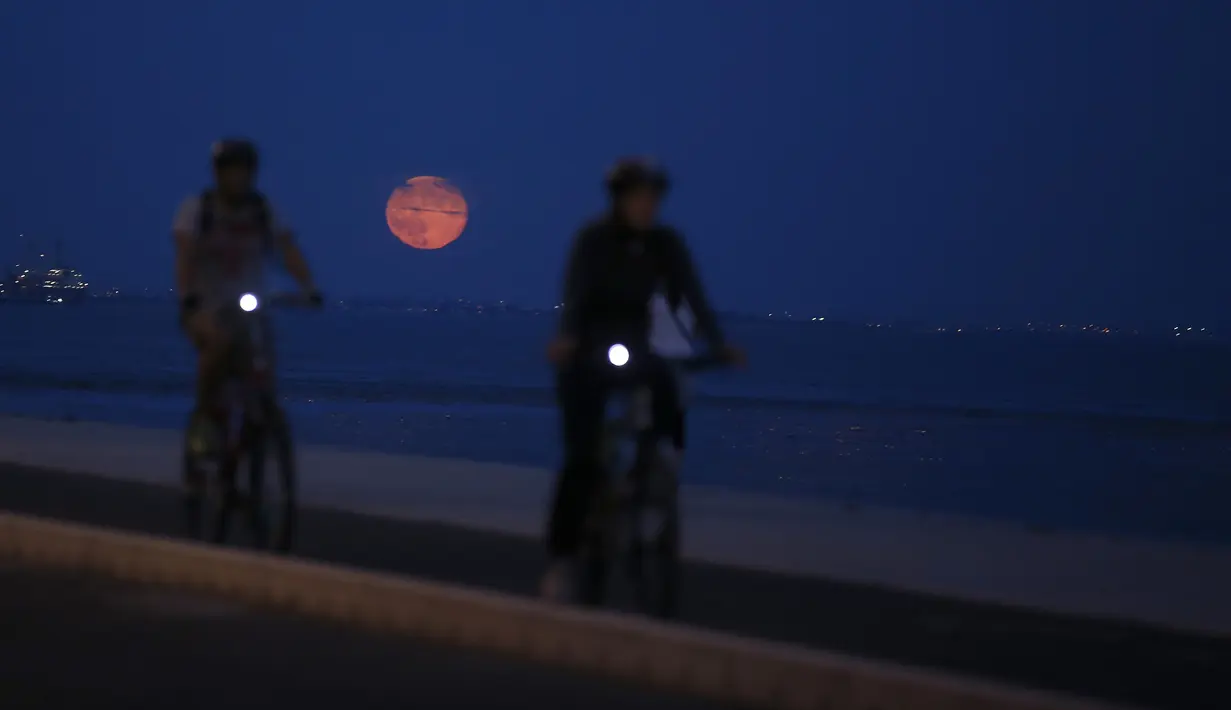 Dua orang pria bermain sepeda dengan latar belakang supermoon, di Lisbon, Portugal, Selasa (9/9/14). (REUTERS/Rafael Marchante)