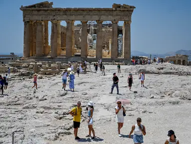 Wisatawan mengunjungi Acropolis di Athena, Yunani, Minggu (24/7/2022). Negara ini berada dalam cengkeraman gelombang panas yang dimulai pada 23 Juli dan akan berlangsung beberapa hari. Suhu diperkirakan akan mencapai 42 derajat Celcius (107 derajat Fahrenheit) di beberapa daerah.
(Louisa GOULIAMAKI / AFP)