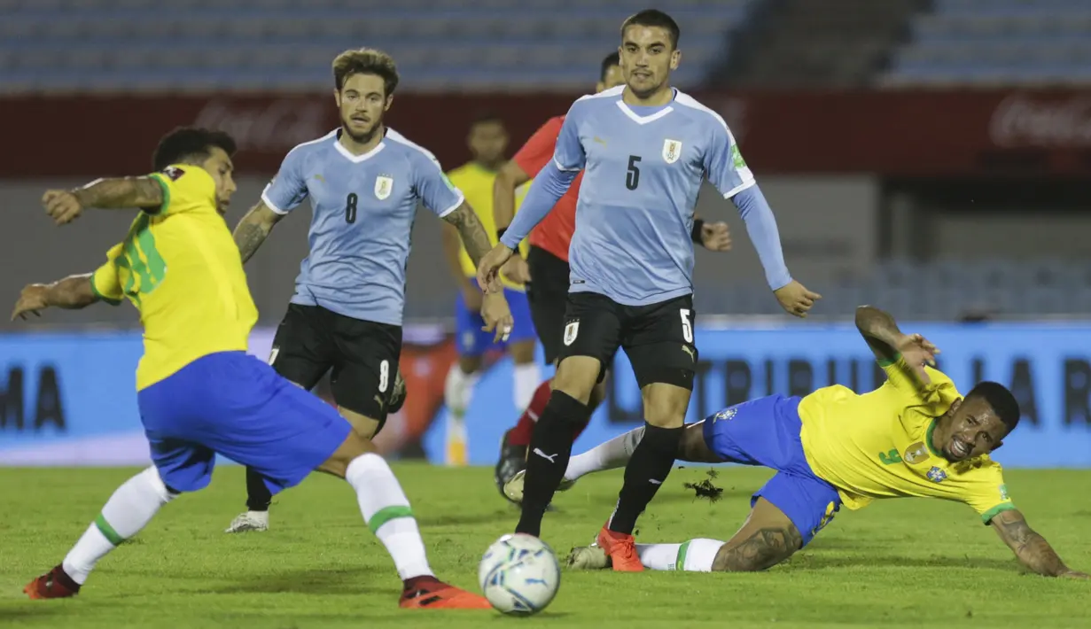 Penyerang Brasil, Roberto Firmino, berebut bola dengan gelandang Uruguay, Nahitan Nandez, pada laga lanjutan kualifikasi Piala Dunia zona CONMEBOL di Estadio Centenario, Rabu (18/11/2020) pagi WIB. Brasil menang 2-0 atas Uruguay. (AFP/Matilde Campodonico/pool)