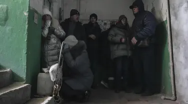 Orang-orang berlindung dari penembakan di dalam pintu masuk gedung apartemen di Mariupol, Ukraina, Minggu, 13 Maret 2022. Pada 24 Februari 2022, Rusia melancarkan invasi berskala besar ke Ukraina, salah satu negara tetangganya di sebelah barat daya. (AP Photo/Evgeniy Maloletka)