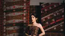 Kain batik yang menjadi aksen utama pada bagian bawah dress memberikan sentuhan tradisional, sementara tambahan outer hitam berukuran besar menciptakan efek dramatis yang begitu kuat. Dipadukan dengan pose editorial dan latar kain tradisional, penampilan Davina terlihat bold, fierce, sekaligus penuh penghormatan terhadap warisan budaya Indonesia. [@davinakaramoy].