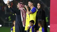 Cristiano Ronaldo bersama sang kekasih Georgina Rodriguez dan anak-anaknya berdiri di atas panggung saat upacara penyambutan dirinya sebagai pemain baru Al Nassr di Stadion Mrsool Park, di ibu kota Saudi, Riyadh, Selasa (3/1/2023). Georgina Rodriquez seperti mengikuti kebudayaan di Arab Saudi dengan mengenakan pakaian yang lebih sopan dan tertutup. (Fayez Nureldine / AFP)