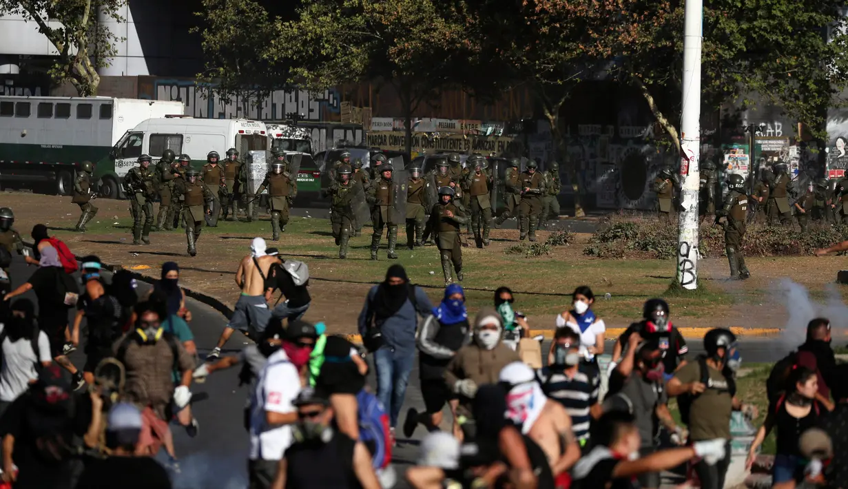 Polisi berlari ke arah demonstran antipemerintah saat protes di Santiago, Chile, Jumat (27/12/2019). Sebagian besar dari daftar panjang tuntutan demonstran Chile berfokus pada ketidaksetaraan. (AP Photo/Fernando Llano)