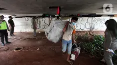 Petugas Satpol PP melakukan razia kepada para tunawisma di bawah flyover Jatinegara, Jakarta Timur, Senin (19/7/2021). Razia ini merupakan upaya dari Kecamatan Jatinegara di kawasan Kampung Melayu untuk bersih dari tunawisma yang sering tidur dan berjualan.  (Liputan6.com/Johan Tallo)