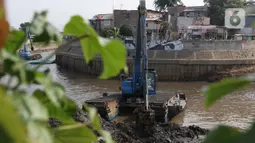 Petugas menggunakan alat berat melakukan proses pengerukan endapan tanah di aliran Sungai Ciliwung, Jakarta, Selasa (28/7/2020). Pengerukan endapan ini untuk memperlancar aliran air Sungai Ciliwung serta upaya pencegahan banjir saat musim hujan. (Liputan6.com/Helmi Fithriansyah)