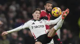 Pemain Fulham, Harry Wilson (kiri) berebut bola dengan pemain Manchester United, Lisandro Martinez pada laga lanjutan Liga Inggris 2024/2025 di Craven Cottage, London, Senin (27/01/2025) dini hari WIB. (AP Photo/Kirsty Wigglesworth)