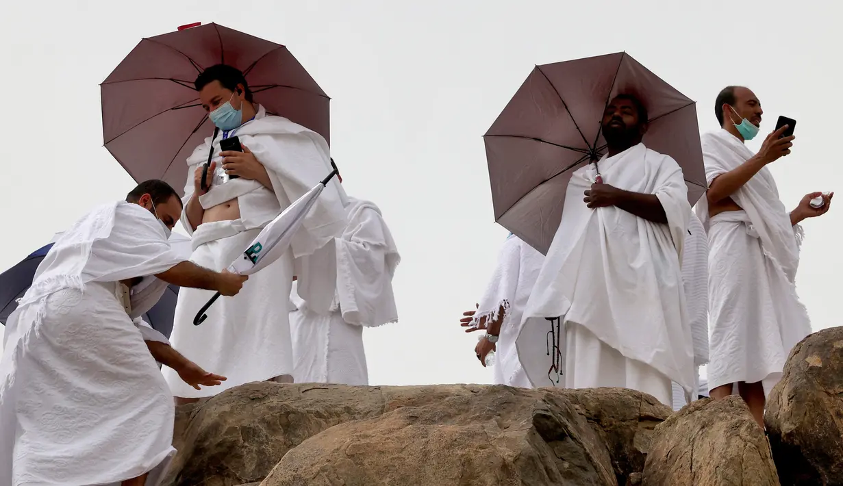 Jemaah haji menaiki Jabal al-Rahma (Gunung Rahmat) saat menunaikan prosesi wukuf di Padang Arafah, tenggara Kota Suci Mekah, Arab Saudi, Senin (19/7/2021). Ibadah haji tahun ini hanya diikuti oleh 60 ribu orang jemaah saja. (FAYEZ NURELDINE/AFP)