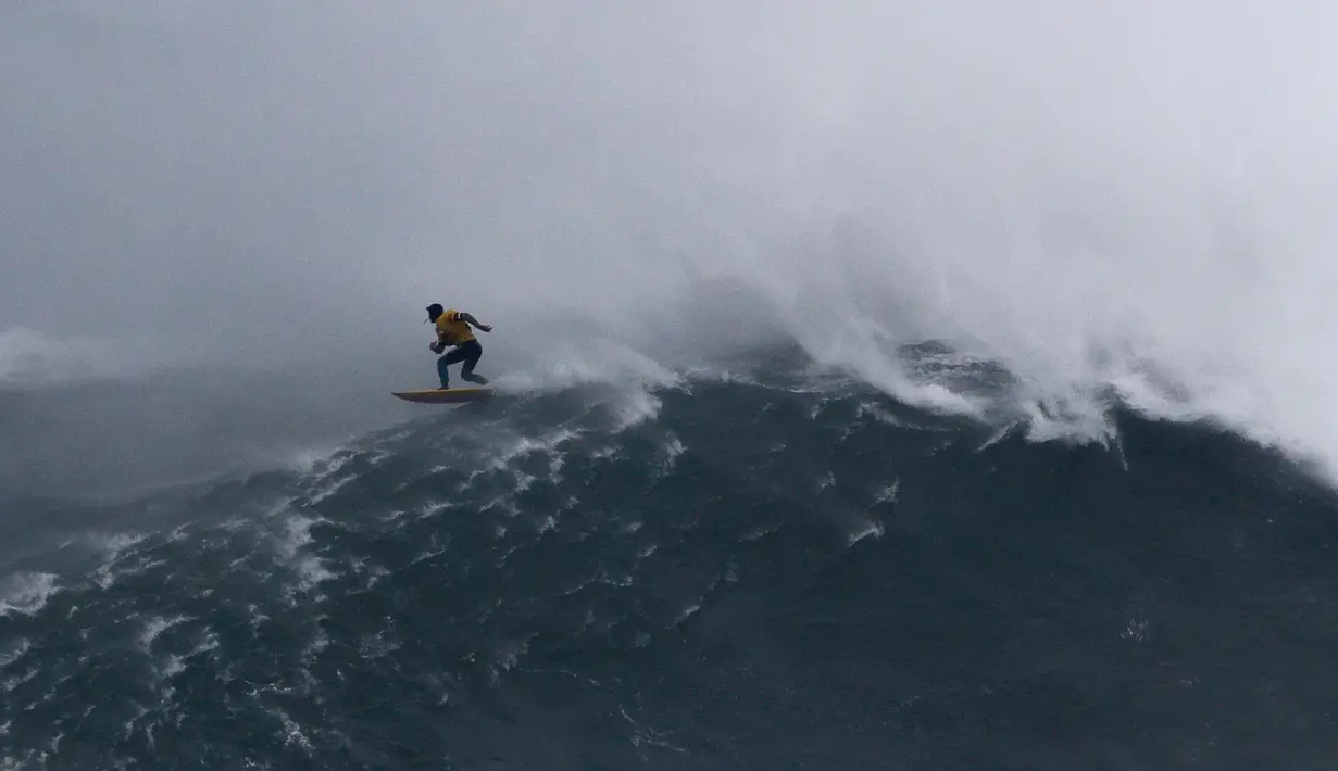 Peselancar Spanyol Axier Muniain berusaha menaklukkan ombak Praia do Norte atau Pantai Utara di Nazare, Portugal, Selasa (11/2/2020). Praia do Norte menjadi tempat uji nyali peselancar dunia karena ombaknya yang bisa mencapai 30 meter. (AP Photo/Armando Franca)