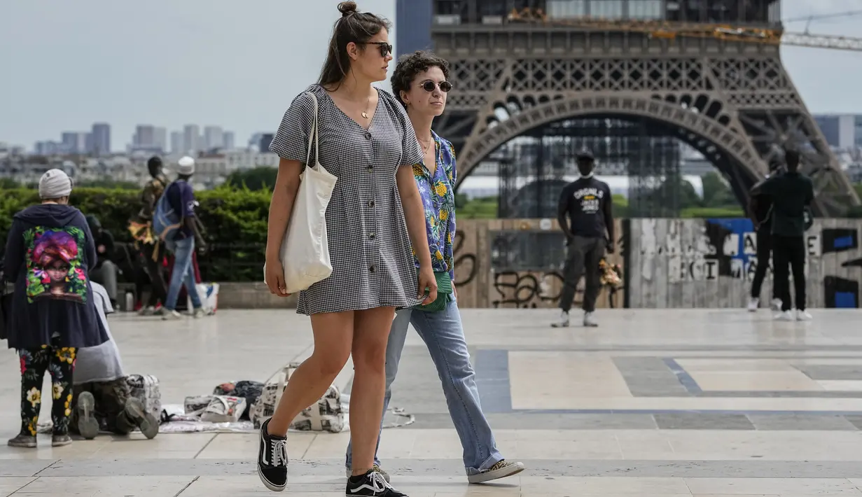 Orang-orang melintasi alun-alun Trocadero dekat Menara Eiffel di Paris, Kamis (17/6/2021). Prancis mengumumkan melonggarkan aturan pembatasan COVID-19, mencabut aturan penggunaan masker di luar ruangan dan menghentikan jam malam mulai pekan ini setelah delapan bulan terakhir. (AP Photo/Michel Euler