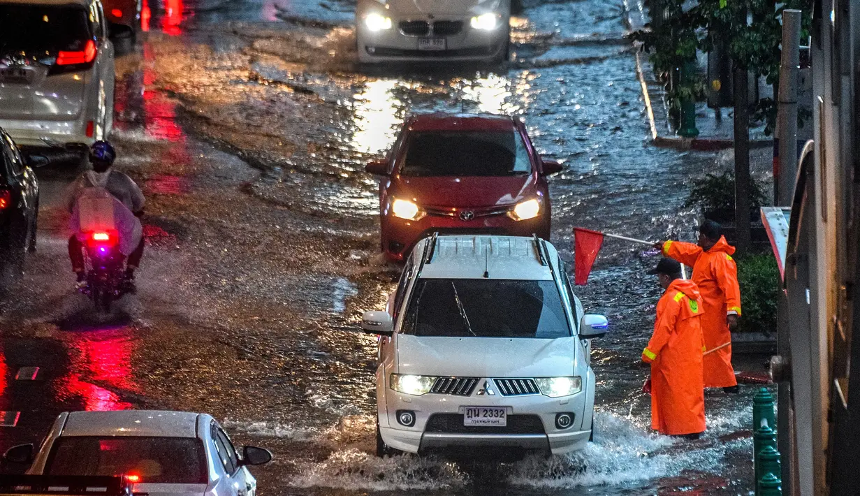 Petugas keamanan mengatur lalu lintas di jalan yang banjir saat hujan deras di Bangkok (23/9/2020). (AFP/Mladen Antonov)