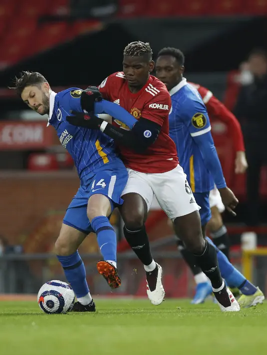 Gelandang Brighton and Hove Albion, Adam Lallana berebut bola dengan gelandang Manchester United, Paul Pogba pada pekan ke 30 Liga Inggris di Old Trafford, Senin dinihari WIB (05/04/2021). MU harus bekerja keras sebelum mengalahkan Brighton 2-1. (Phil Noble/Pool via AP)