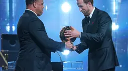 Pesepak bola Inggris, Harry Kane, menerima trofi penghargaan pemain terbaik dari mantan pesepak bola Brasil, Ronaldo Nazario, dalam acara penganugerahan Ballon d&rsquo;Or di London Palladium Theatre, London, Inggris, Senin (26/10/2026). (AP Photo/Kin Cheung)