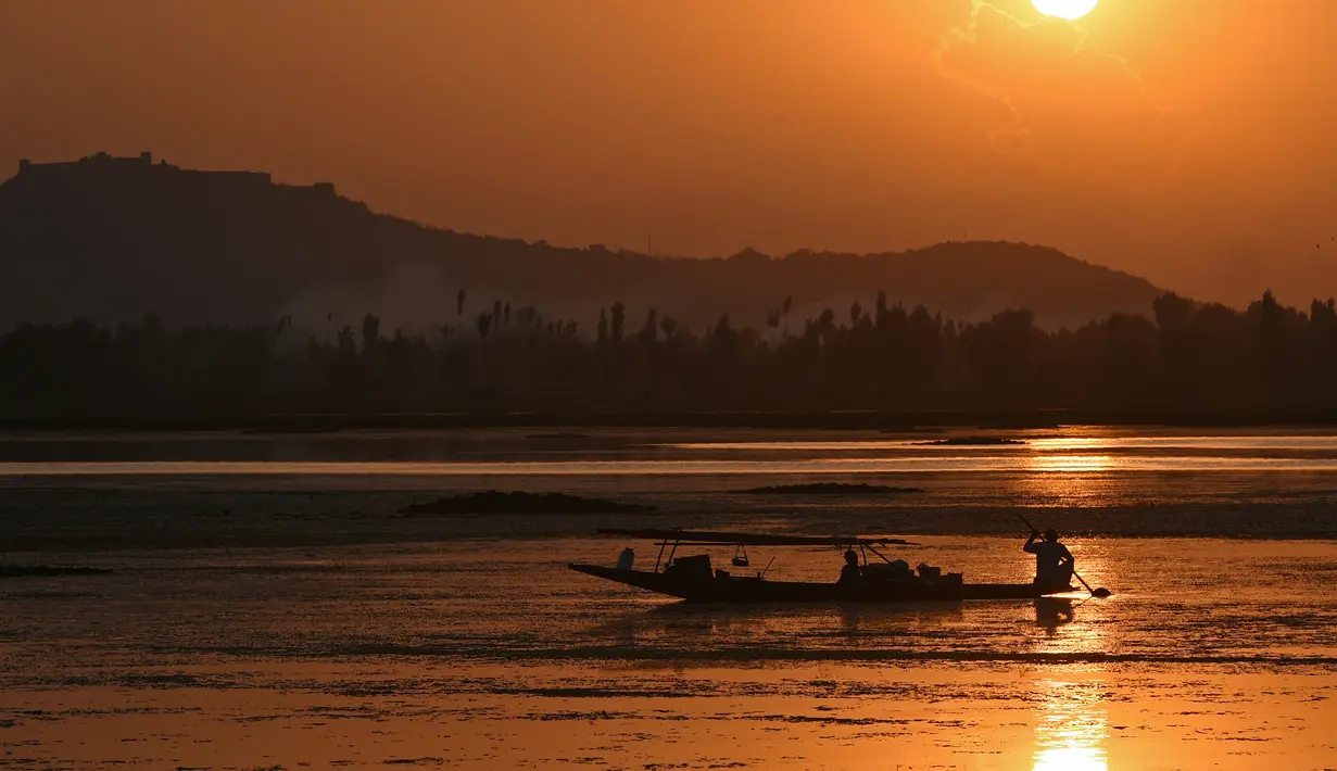 Seorang nelayan Kashmir mengayuh perahunya saat matahari terbenam di danau Dal di Srinagar, India (12/9). Danau Dal dijuluki sebagai Jewel in the Crown of Kashmir atau Srinagar Jewel. (AFP Photo/Tauseef Mustafa)