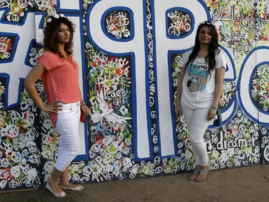 Dua gadis cantik berpose di depan lukisan abstrak saat mengunjungi festival memperingati Hari Perdamaian Internasional di Baghdad, Irak (21/9/2015). Perayaan diisi dengan kreativitas seni karya para pemuda dan pemudi Irak. (REUTERS/Thaier al-Sudani)