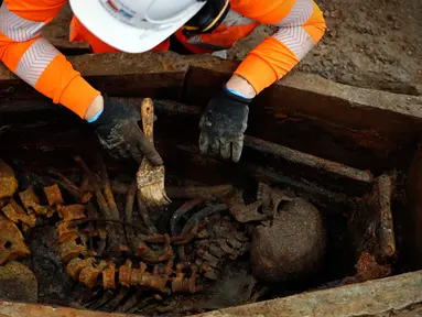 Arkeolog membersihkan kerangka dalam peti mati saat penggalian pemakaman di bawah St James Gardens, London, Inggris, Kamis (1/11). Lokasi pemakaman berada dekat Stasiun Euston. (ADRIAN DENNIS/AFP)