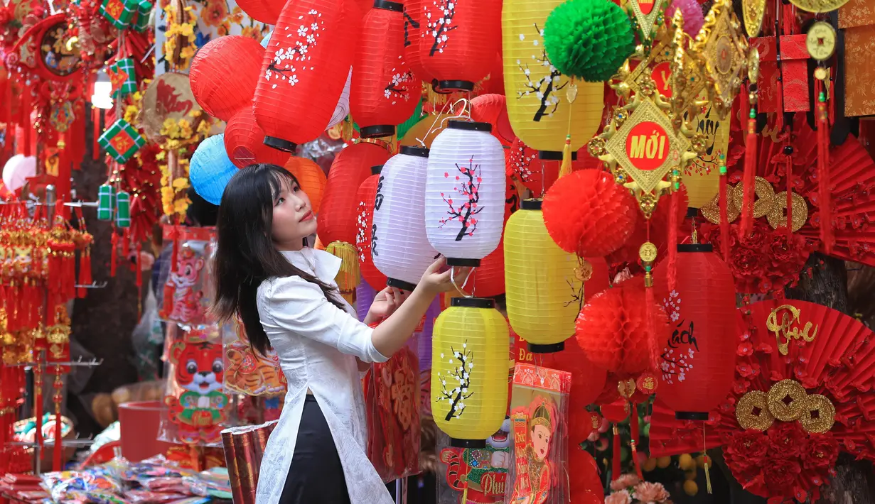 Seorang wanita melihat lentera di pasar tradisional Tahun Baru Imlek "Tet" di kawasan tua Hanoi, Vietnam, Jumat (28/1/2022). Vietnam merayakan Tahun Baru Imlek yang akan datang di tengah peringatan terhadap perjalanan dan pertemuan besar karena COVID -19. (AP Photo/Hau Dinh)
