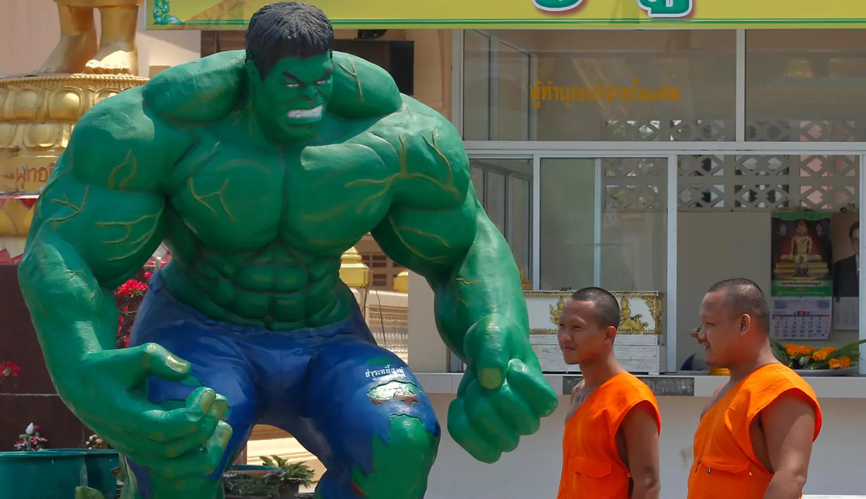 Dua orang biksu melintas di dekat patung "Hulk" di kuil Tamru di Samut Prakan, Thailand (3/3). Pihak Candi mengatakan telah menyiapkan patung-patung karakter komik Marvel untuk menarik pengunjung. (REUTERS/Chaiwat Subprasom)