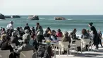Warga dan turis menikmati minuman di sebuah kafe selama cuaca musim dingin yang hangat di sepanjang garis pantai kota Biarritz di Perancis barat (17/2). Kota ini terletak di region Aquitane, Departemen Pyrénées-Atlantiques. (AFP Photo/Iroz Gaizka)