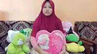 Azahra Zenita Putri, adik keempat dari Indah Halimah Putri, penumpang Sriwijaya Air SJ-182 yang mengalami kecelakaan pada Sabtu (9/1/2021) lalu, berfoto bersama boneka pemberian kakak perempuannya (Liputan6.com / Nefri Inge)