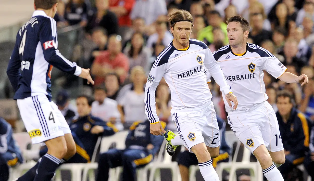 Pemain LA Galaxy, David Beckham (tengah) and Robbie Keane terlihat saat laga persahabatan melawan Melbourne Victory di Melbourne,  Australia, 6 December 2011. Beckham bergabung dengan LA Galaxy pada taun 2007. Ia berhasil menorehkan 124 pertandingan dengan mencetak 20 gol dan 42 assist sebelum hengkang pada 2013. Sementara Robbie Keane tercatat berhasil mencetak 104 gol dan 41 assist dalam 165 pertandingan bersama LA Galaxy sejak tahun 2011 hingga 2017. (AFP/William West)
