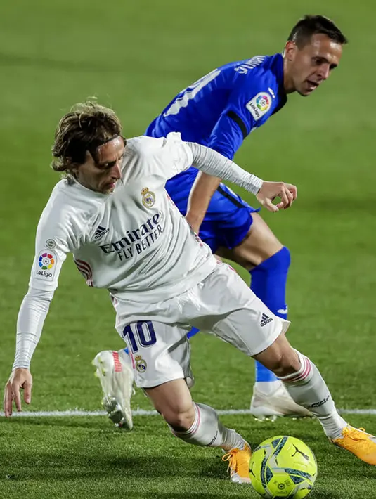 Pemain Real Madrid Luka Modric (depan) memperebutkan bola dengan pemain Getafe Nemanja Maksimovic pada pertandingan Liga Spanyol di Stadion Alfonso Perez, Getafe, Spanyol, Minggu (18/42021). Pertandingan berakhir dengan skor 0-0. (AP Photo/Manu Fernandez)