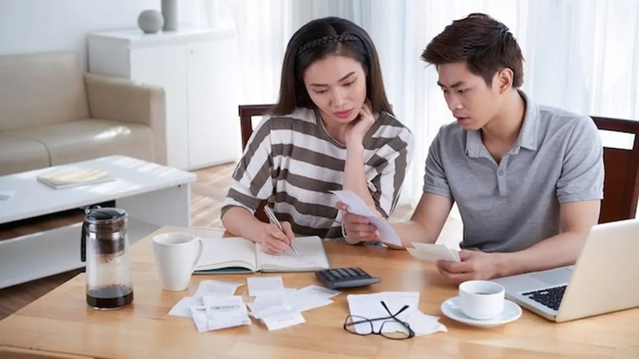 Pasangan Suami Istri Sedang Mencatat Pengeluaran di Buku