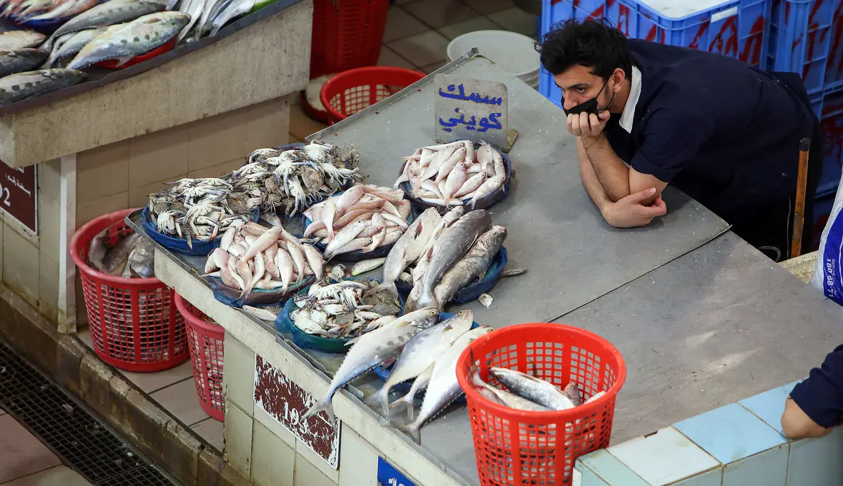 Seorang penjual menunggu pelanggan selama pelelangan di pasar ikan di Kuwait City (8/8/2021). Pelelangan dibuka kembali di negara itu setelah enam bulan ditutup di tengah pandemi virus corona. (AFP/ Yasser Al-Zayyat)