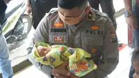 Kapolsek Tampan Kompol Hotmartua Ambarita menggendong bayi yang dibuang orangtuanya di salah satu panti asuhan di Pekanbaru. (Liputan6.com/M Syukur)