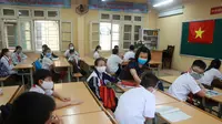 Seorang guru memeriksa suhu murid-muridnya sebelum memulai kelas di sekolah menengah Dinh Cong di Hanoi pada hari Senin. Siswa di seluruh Vietnam kembali bersekolah setelah tiga bulan belajar online. (Hau Dinh / AP)