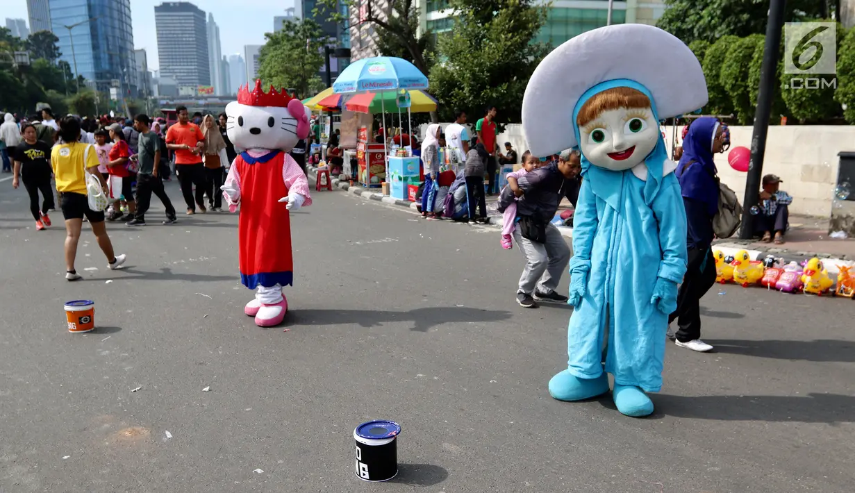 Dua seniman berkostum Hello Kitty dan Masha menunggu warga yang ingin foto bersama saat kegiatan Car Free Day di Bundaran HI di Jakarta, Minggu, (12/11). (Liputan6.com/Fery Pradolo)