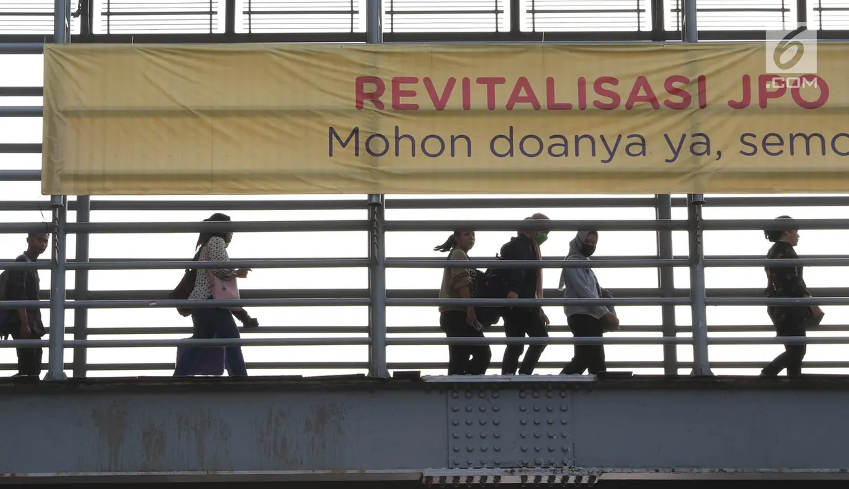 Pejalan kaki melintas di JPO Jalan Sudirman yang dipasangkan Spanduk peringatan revitalisasi, Jakarta (6/11). Tiga JPO yang akan direvitalisasi JPO Bundaran Senayan, JPO Polda Metro Jaya, dan JPO di Stadion Utama GBK. (Liputan6.com/Immanuel Antonius)