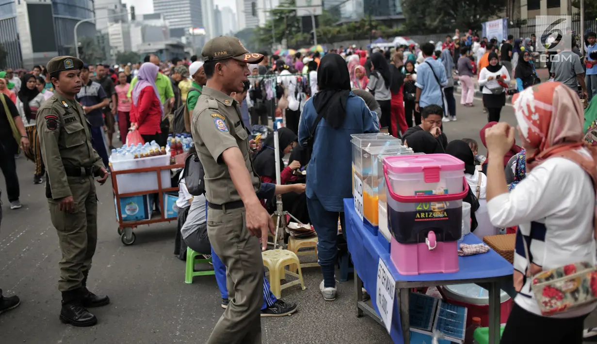 Satpol PP DKI Jakarta menertibkan PKL yang berdagang di kawasan Car Free Day, Bundaran HI, Jakarta, Minggu (20/1). Penertiban dilakukan karena telah membuat ketidaknyamanan bagi para pengunjung CFD yang ingin berolahraga. (Liputan6.com/Faizal Fanani)