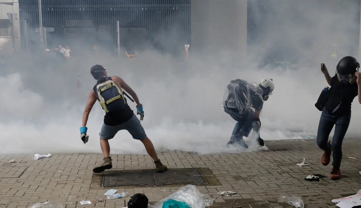 Para pengunjuk rasa melempar gas air mata ke polisi anti huru hara di luar gedung Dewan Legislatif, Hong Kong, Rabu (12/6/2019). Bentrok diawali ketika para pengunjuk rasa merangsek melewati garis polisi dan memaksa masuk ke gedung Dewan Legislatif. (AP Photo/Vincent Yu)