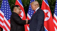 Presiden Amerika Serikat (AS) Donald Trump  berjabat tangan dengan Pemimpin Korea Utara, Kim Jong-un dalam pertemuan bersejarah di resor Capella, Pulau Sentosa, Singapura, Selasa (12/6). Trump dan Kim berjabat tangan untuk pertama kalinya. (AP/Evan Vucci)