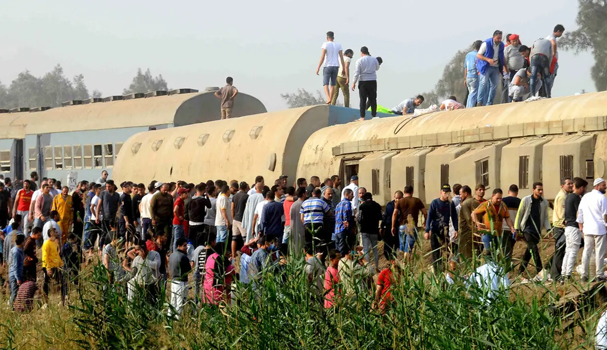 Orang-orang berkumpul di lokasi kecelakaan kereta penumpang dekat Banha, Provinsi Qalyubia, Mesir, Minggu (18/4/2021). Sebanyak 11 orang tewas dan 98 lainnya luka-luka akibat kereta tergelincir dan keluar jalur. (AP Photo/Tarek Wagih)